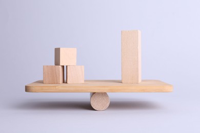 Photo of Equality concept. Seesaw scale with wooden blocks on light background