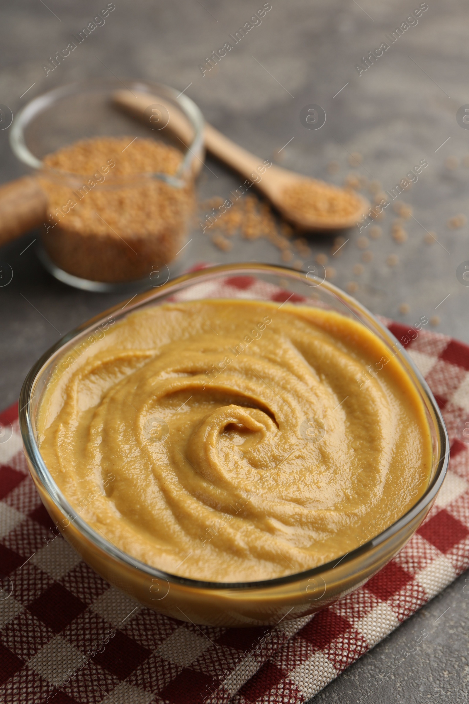 Photo of Tasty mustard sauce in glass bowl on grey table