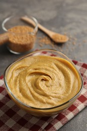 Photo of Tasty mustard sauce in glass bowl on grey table