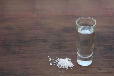 Photo of Mexican tequila shots with salt on wooden table. Space for text