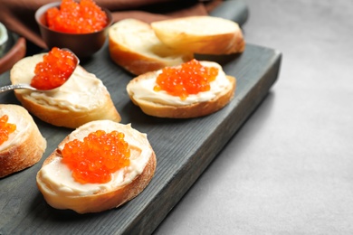 Photo of Delicious sandwiches with red caviar on wooden board