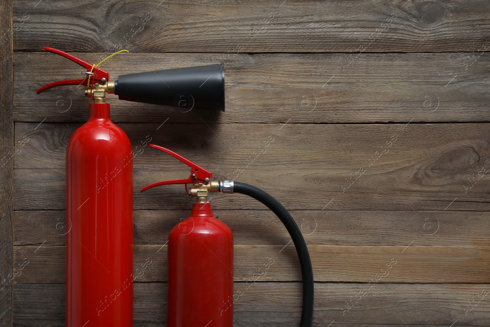 Photo of Two fire extinguishers on wooden background, flat lay. Space for text