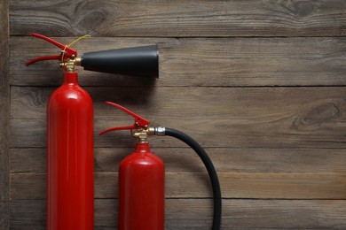 Photo of Two fire extinguishers on wooden background, flat lay. Space for text
