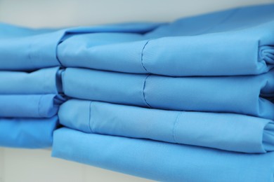 Photo of Light blue medical uniforms on white rack, closeup