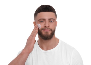 Photo of Handsome man applying cream onto his face on white background