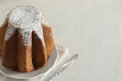 Photo of Delicious Pandoro cake decorated with powdered sugar on white table, closeup and space for text. Traditional Italian pastry