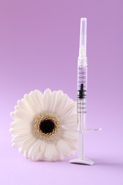 Photo of Cosmetology. Medical syringe and gerbera flower on violet background