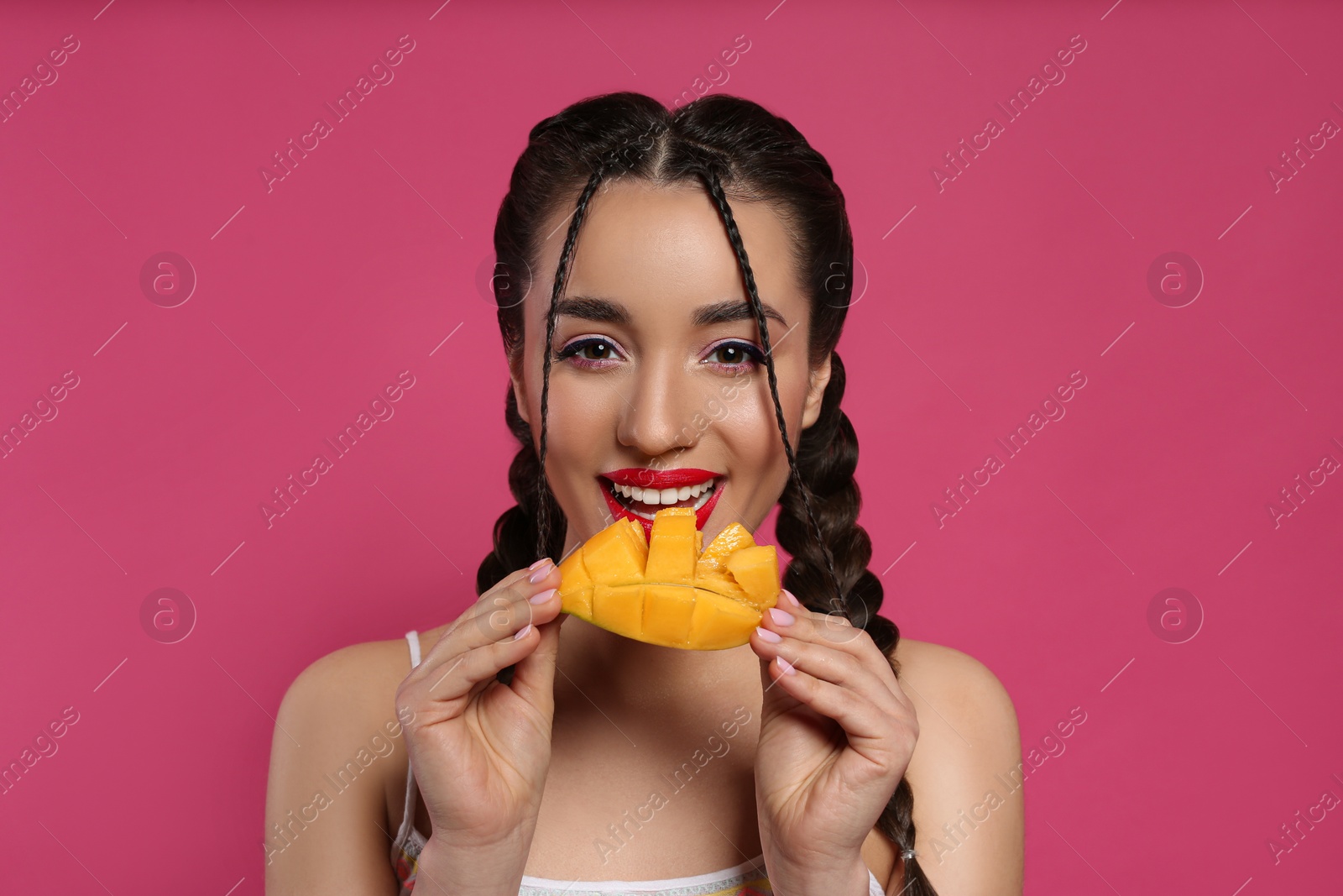 Photo of Young woman with fresh mango on pink background. Exotic fruit