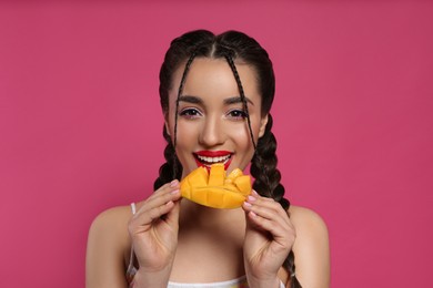 Young woman with fresh mango on pink background. Exotic fruit