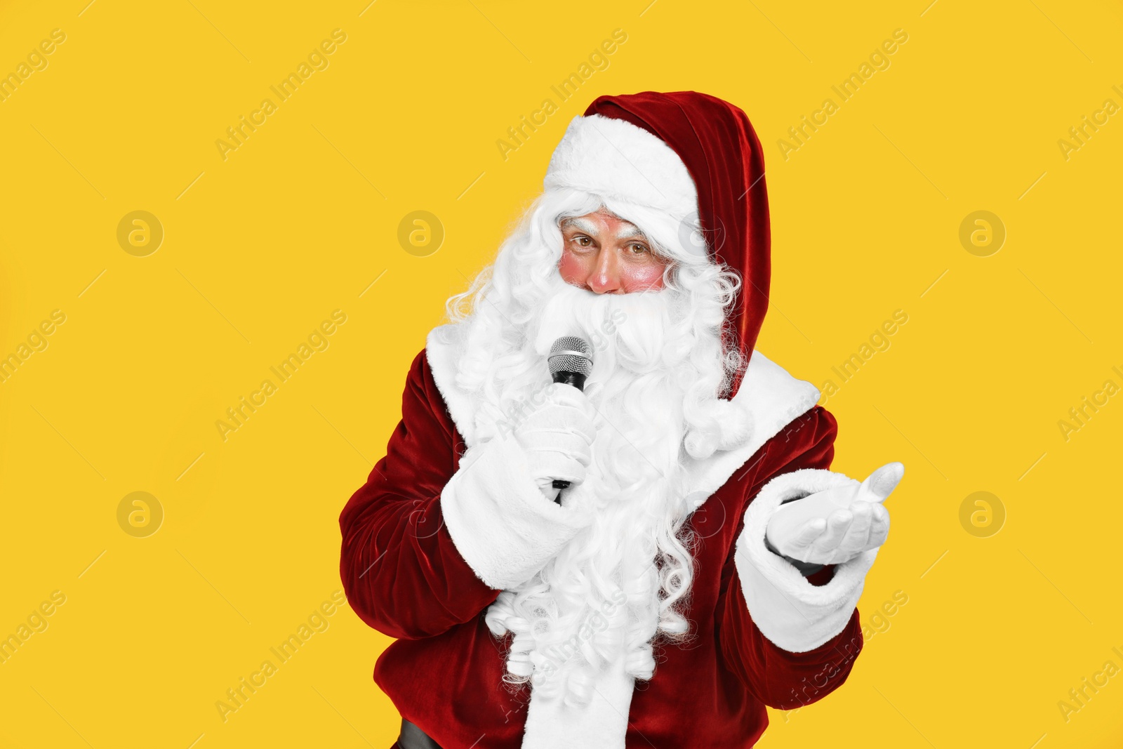 Photo of Santa Claus singing with microphone on yellow background. Christmas music