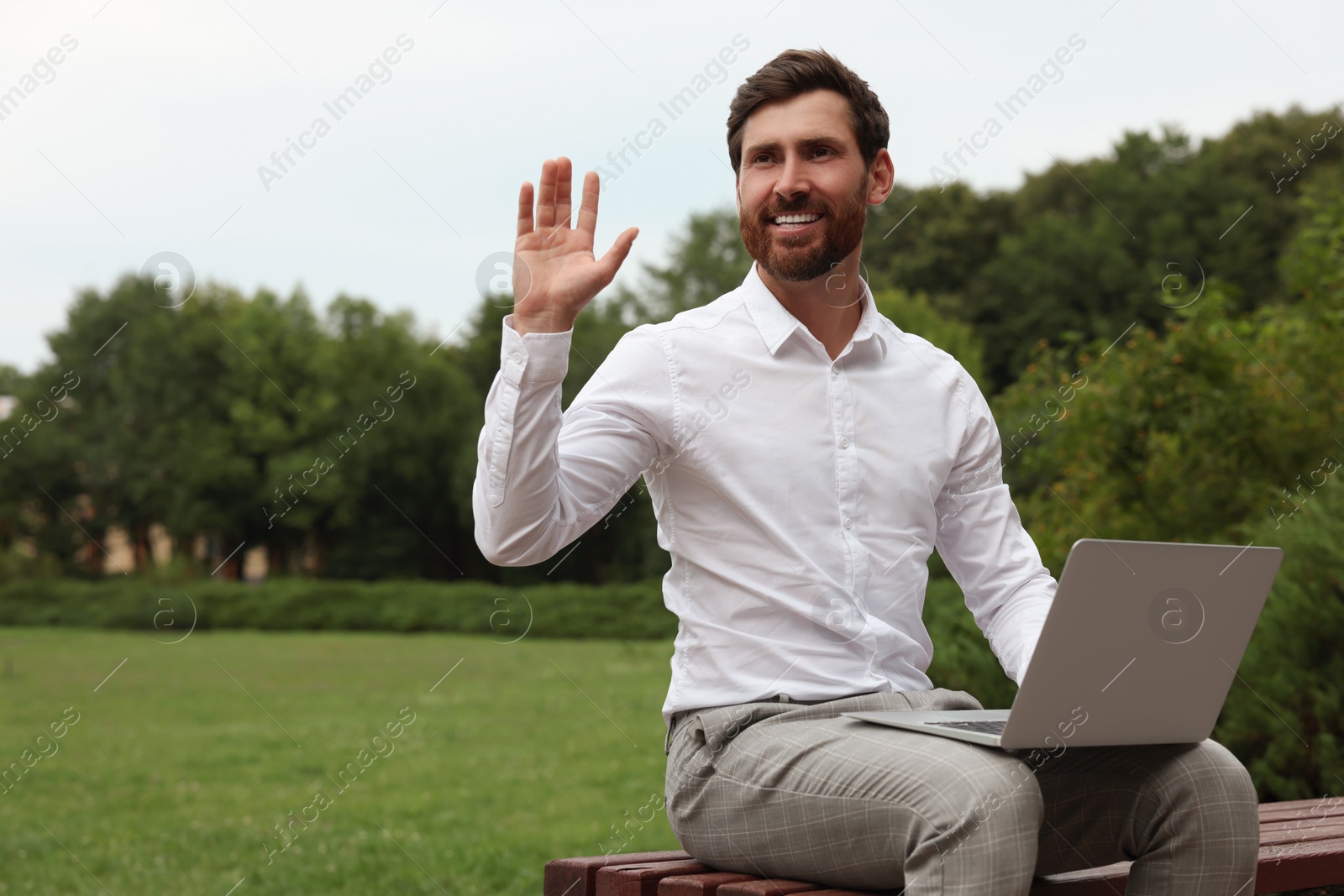 Photo of Handsome businessman with laptop on bench in park