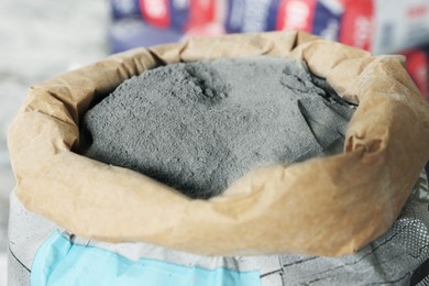 Photo of Cement powder in bag on blurred background, closeup view