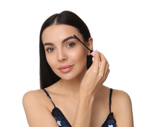 Beautiful young woman applying mascara on white background