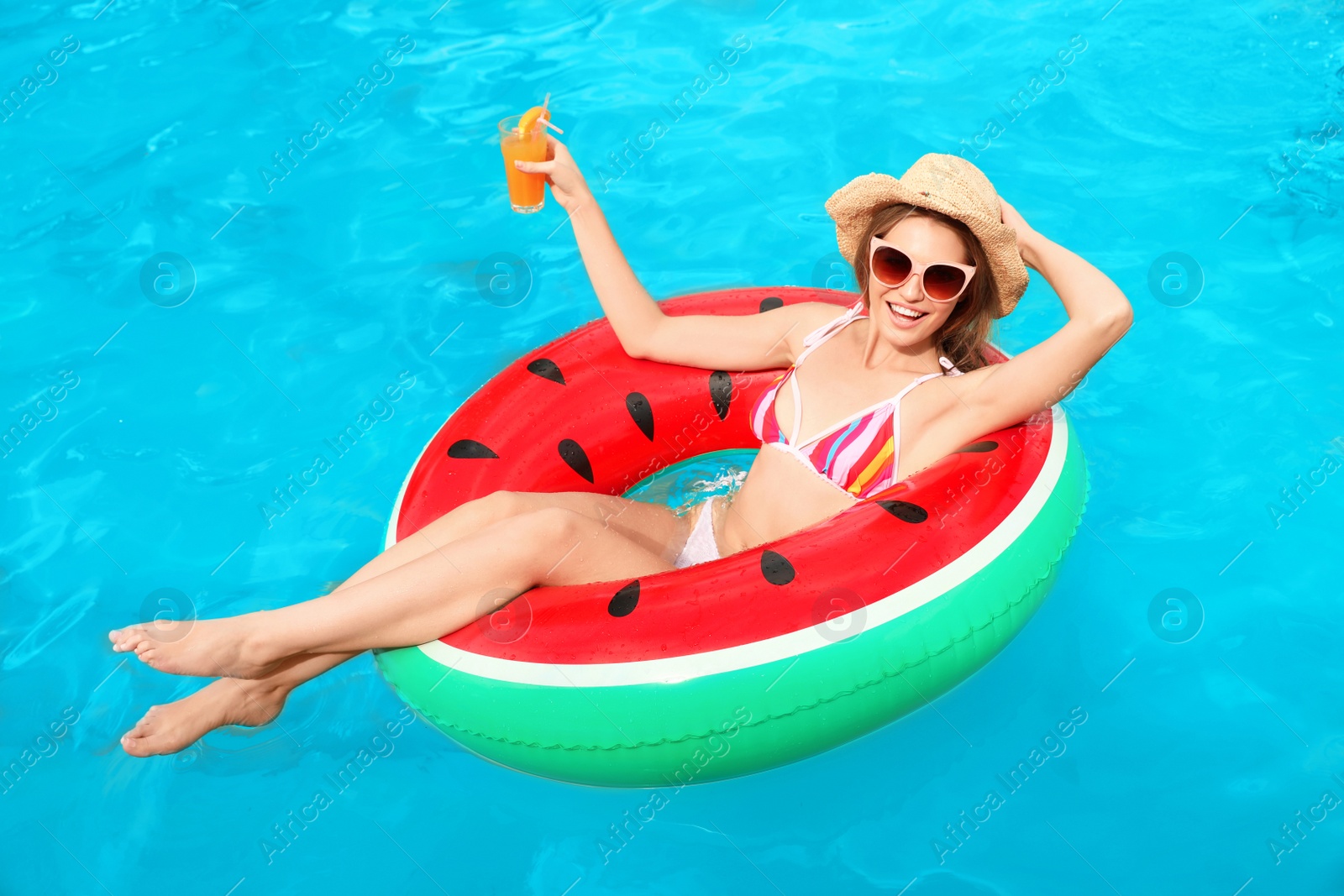 Photo of Young woman with cocktail in pool on sunny day