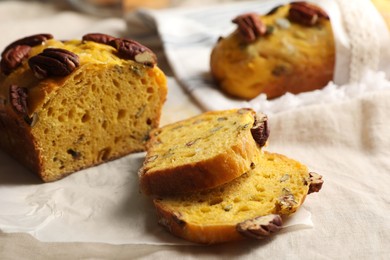 Photo of Delicious pumpkin bread with pecan nuts on tablecloth, closeup