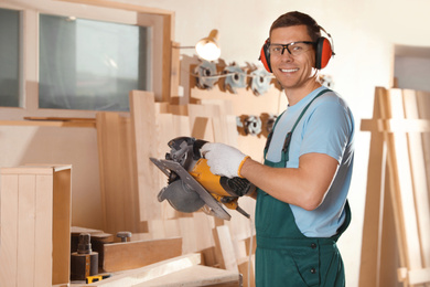 Photo of Professional carpenter with circular saw in workshop