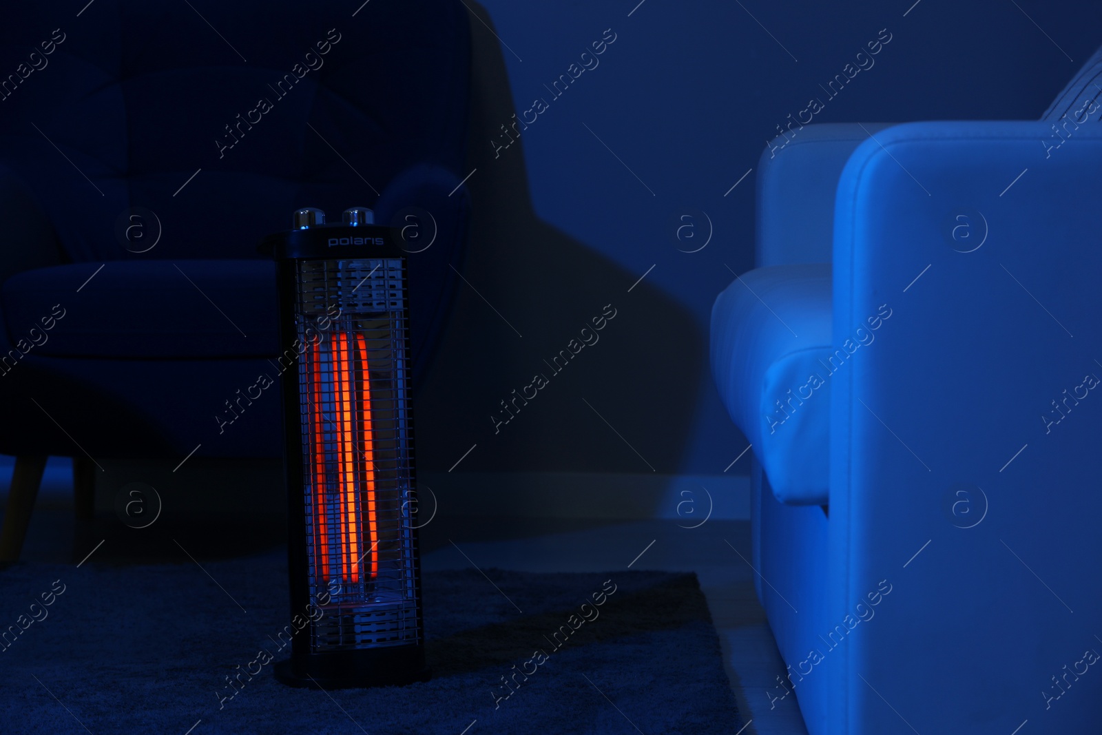 Photo of Electric infrared heater in dark living room at night