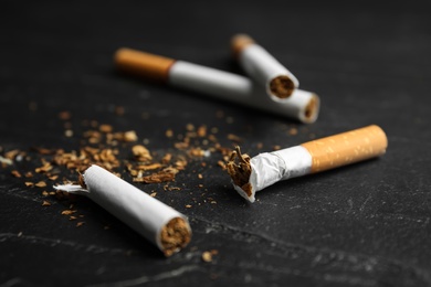 Broken and whole cigarettes on black table, closeup. Quitting smoking concept