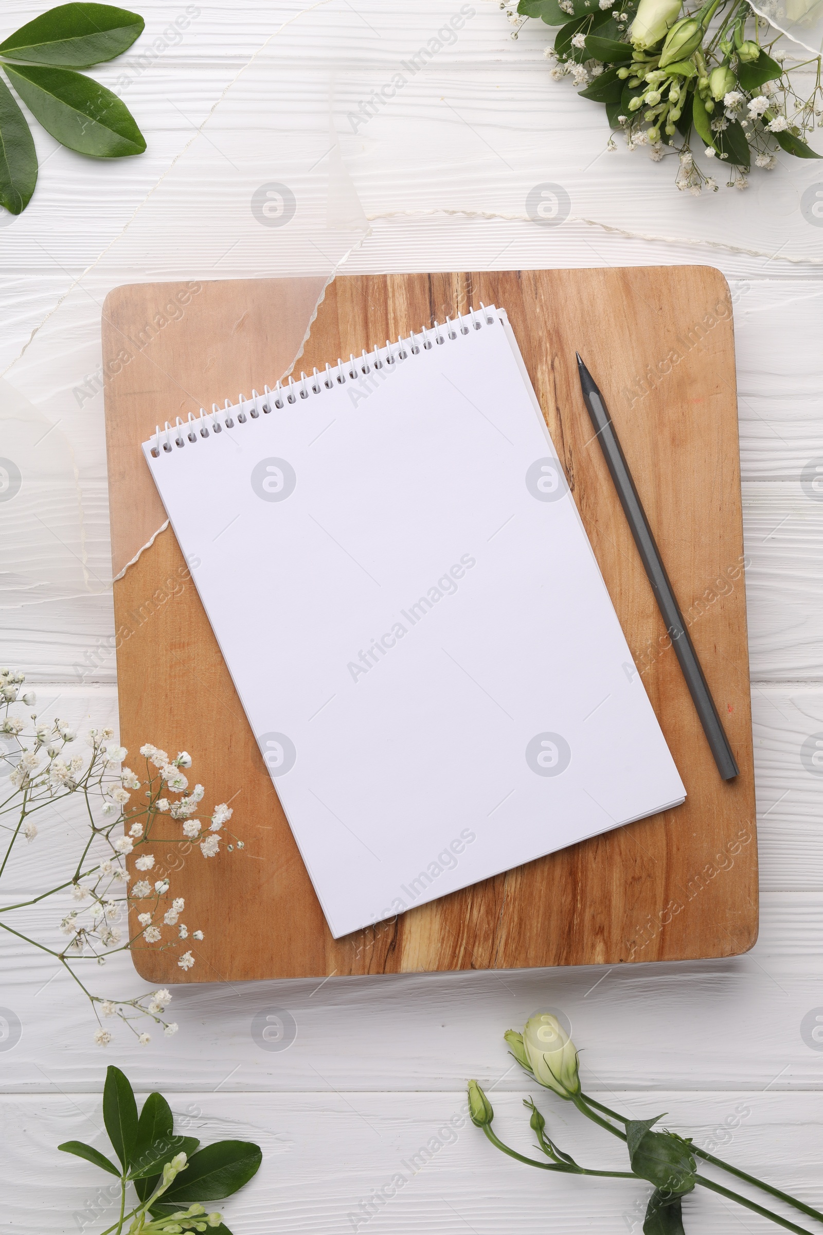 Photo of Guest list. Notebook, pencil, beautiful flowers and ribbon on white wooden background, flat lay