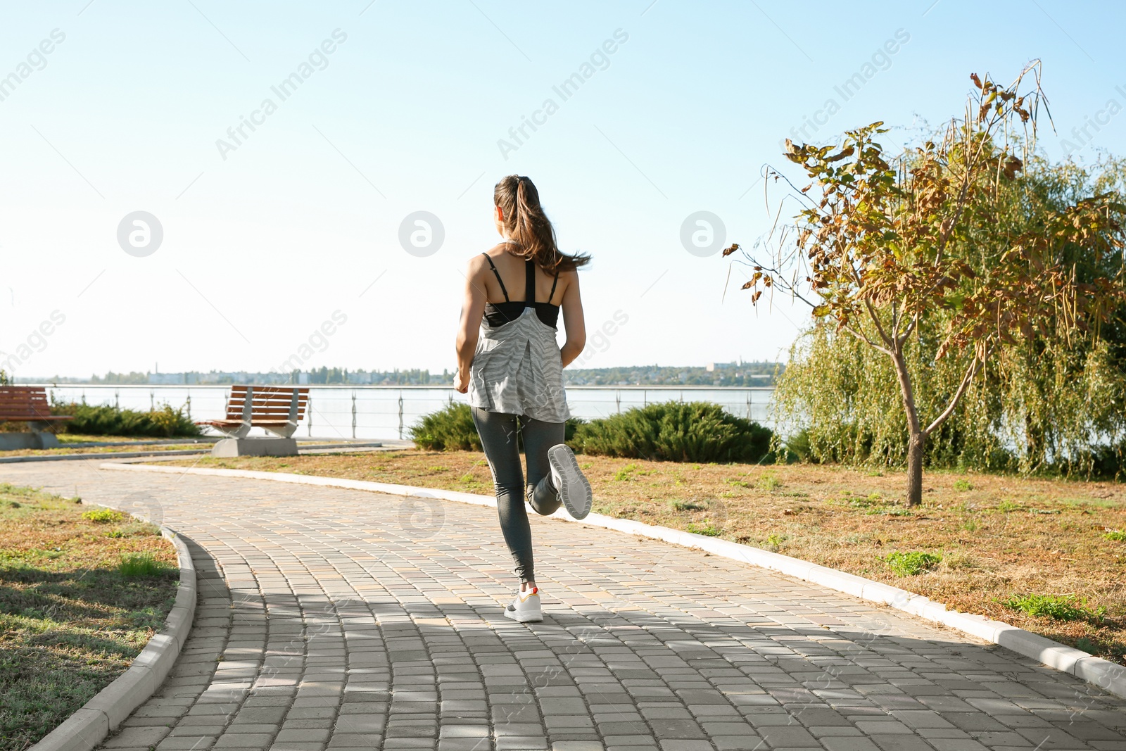 Photo of Sporty woman running outdoors on sunny morning