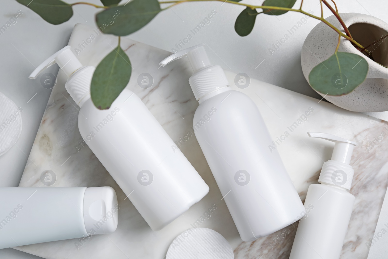 Photo of Different face cleansing products and eucalyptus leaves on white table, flat lay
