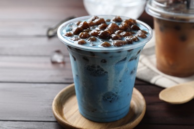 Photo of Tasty blue milk bubble tea on brown wooden table, closeup