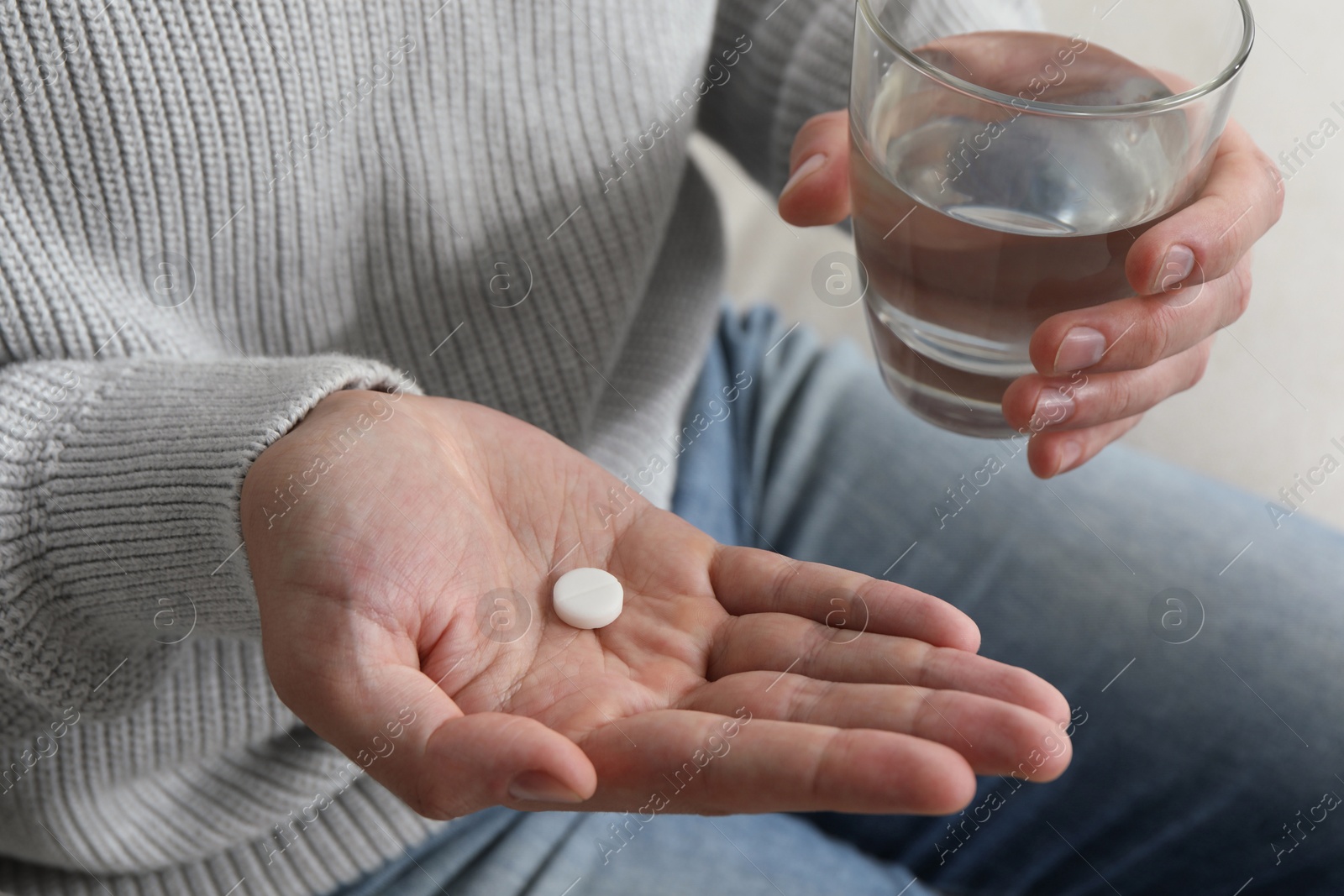 Photo of Man with glass of water and pill on blurred background, closeup