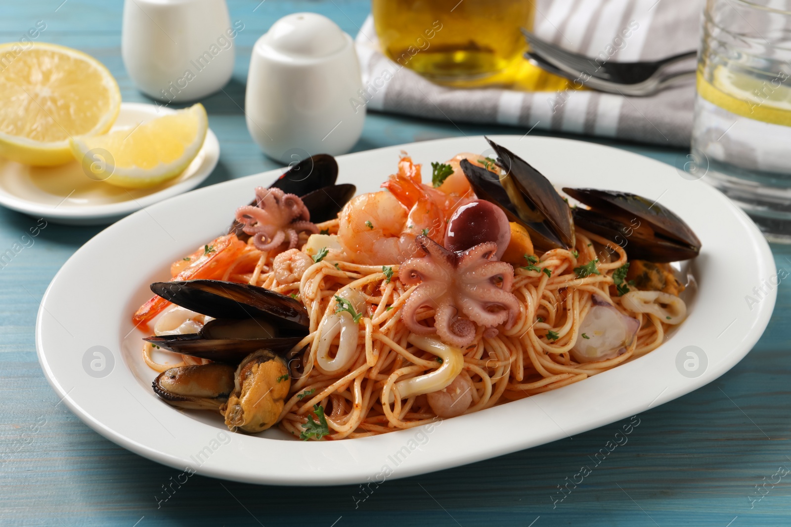 Photo of Delicious spaghetti with seafood served on turquoise wooden table, closeup