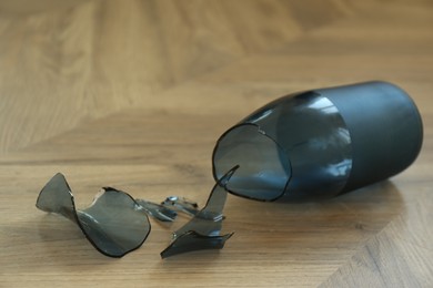 Photo of Broken blue glass vase on wooden floor, closeup