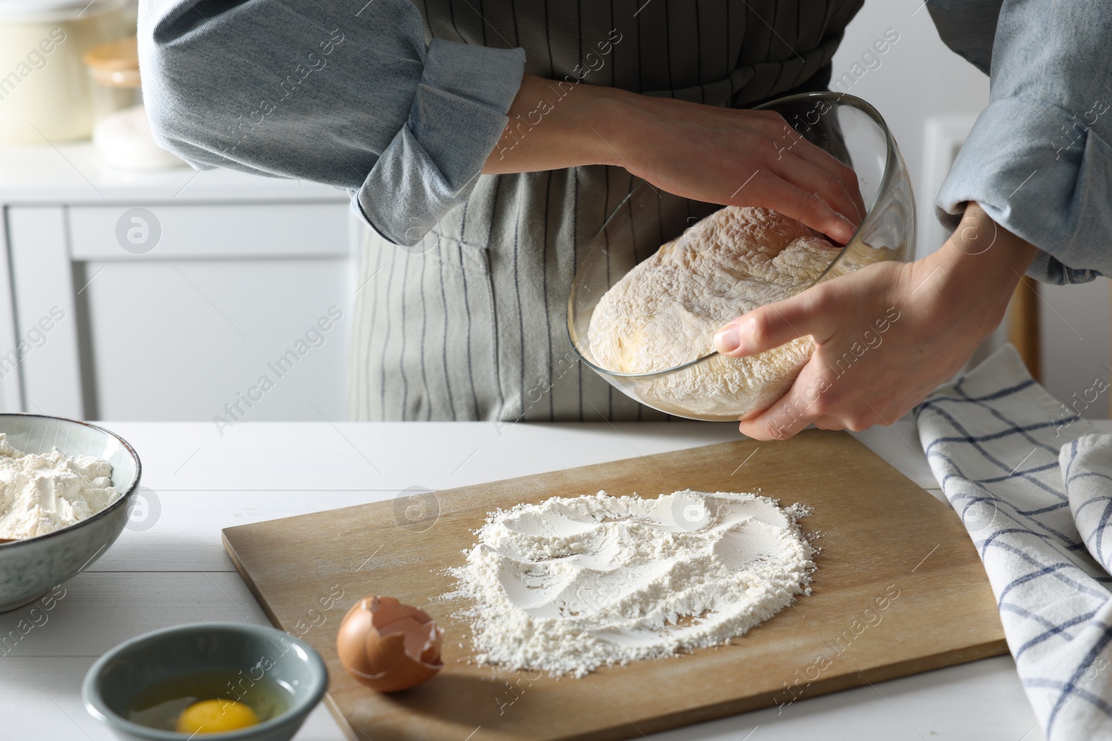 Photo of Woman kneading dough at white wooden table in kitchen, closeup