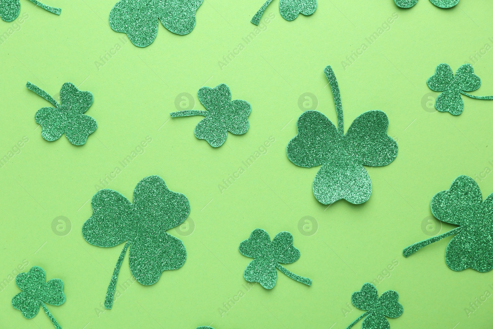 Photo of St. Patrick's day. Decorative clover leaves on green background, flat lay