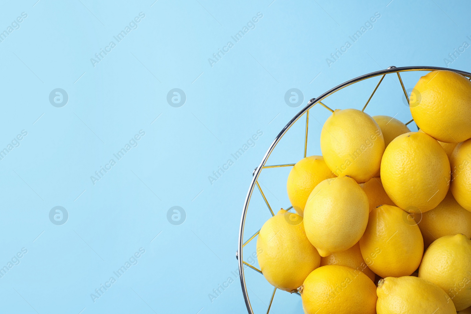 Photo of Ripe fresh lemon fruits on light blue background, top view. Space for text