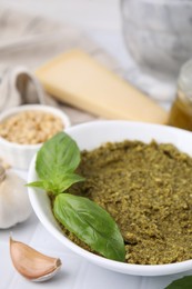 Photo of Bowl with tasty pesto sauce and fresh basil on white table, closeup