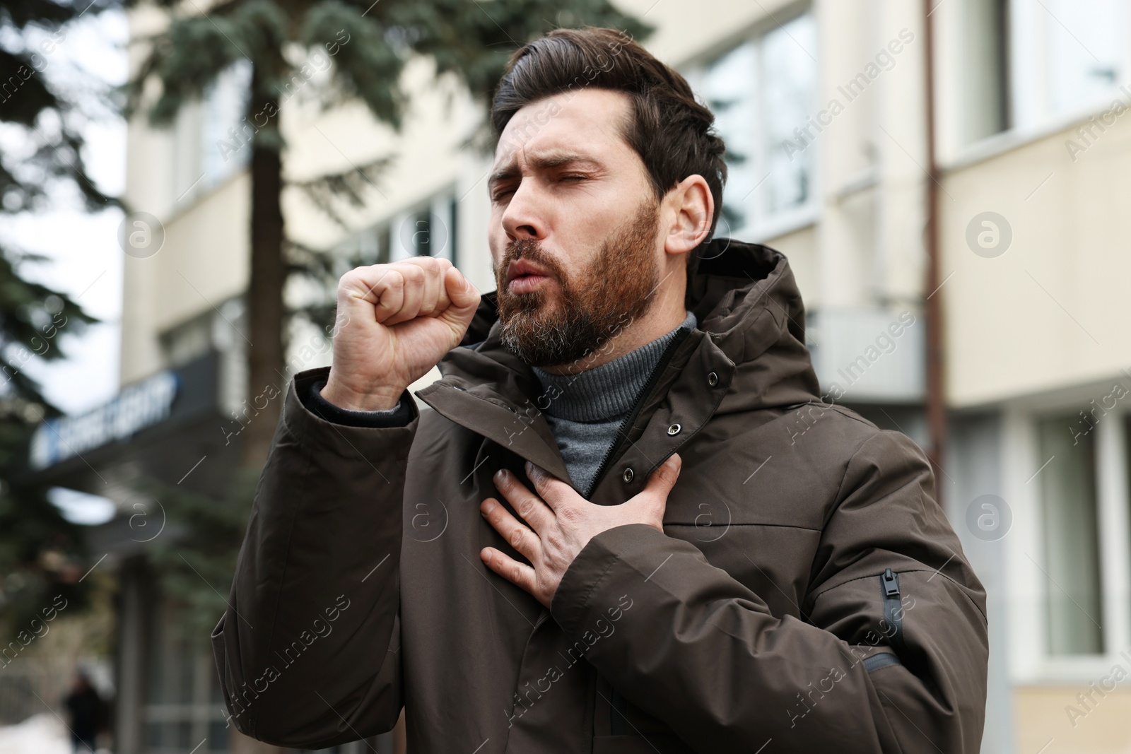 Photo of Sick man coughing on city street. Cold symptoms