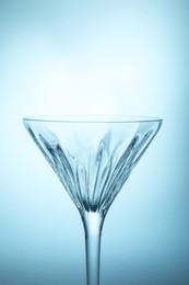 Photo of Elegant empty martini glass on light blue background, closeup. Space for text