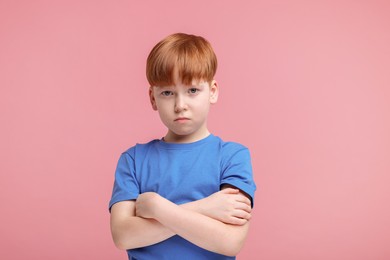 Portrait of sad little boy on pink background