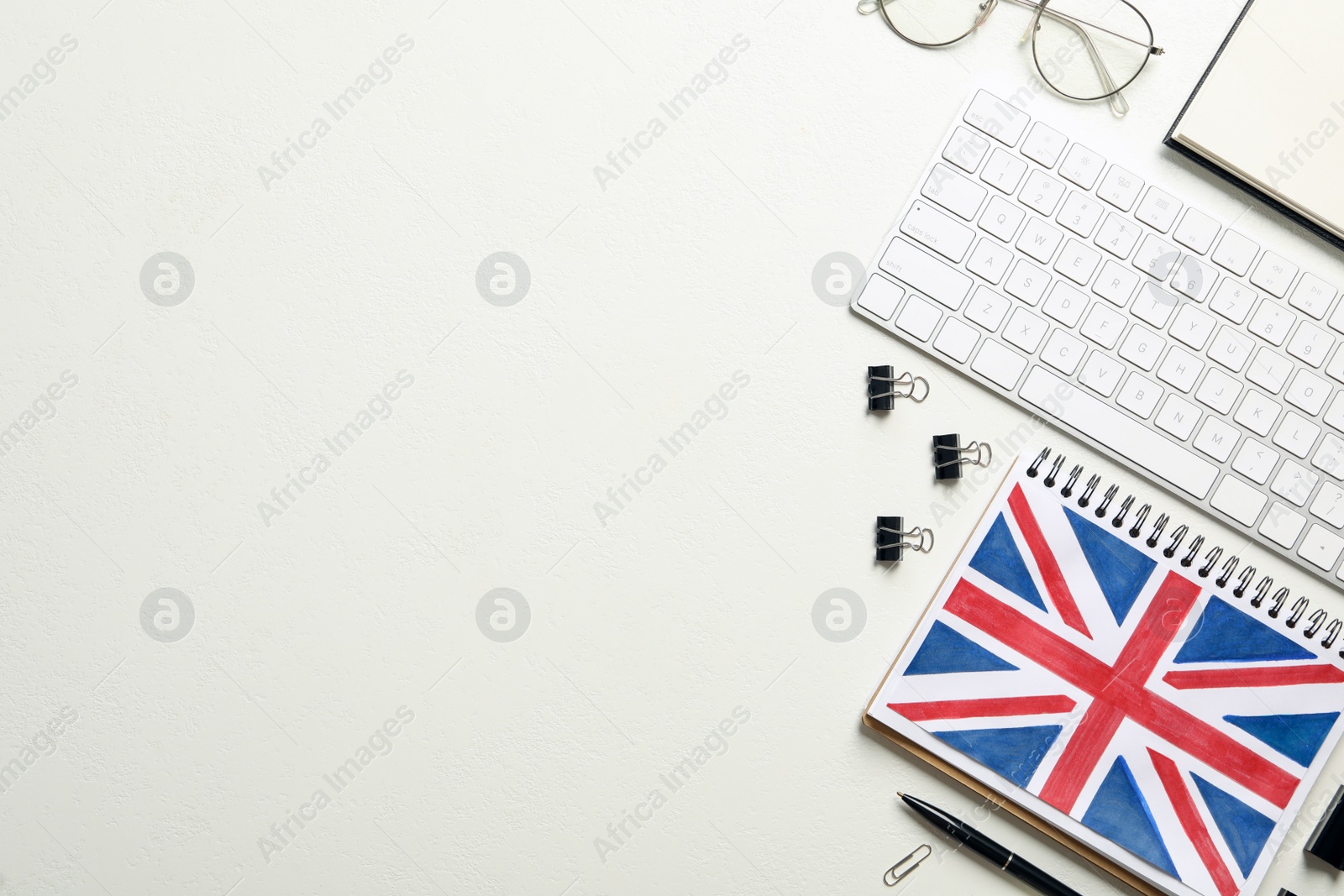 Photo of Notepad, keyboard and stationery on white background, flat lay with space for text. Learning English