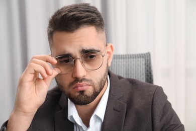 Photo of Portrait of sad businessman wearing glasses in office