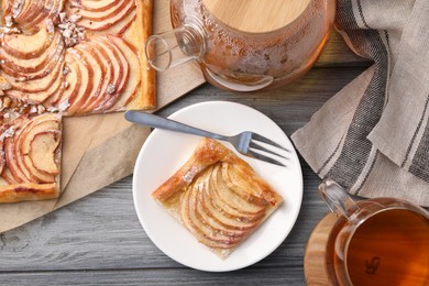 Photo of Tasty apple pie served with tea on grey wooden table, flat lay