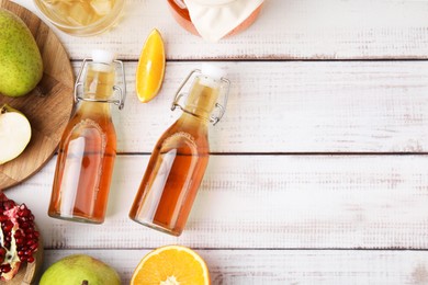 Photo of Tasty kombucha and fresh fruits on white wooden table, flat lay. Space for text