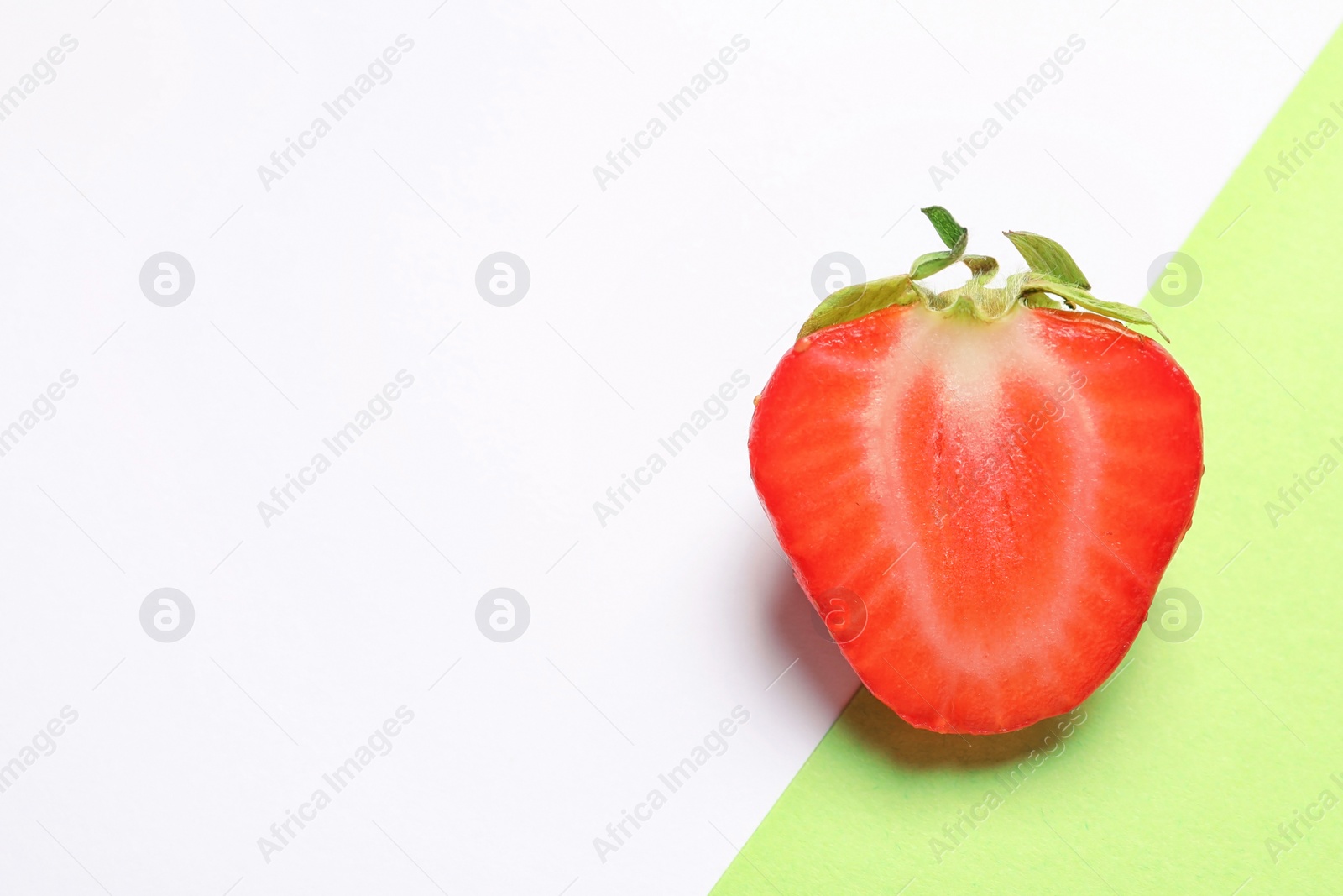 Photo of Half of ripe strawberry on color background, top view