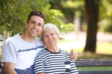 Photo of Man with elderly mother on bench in park