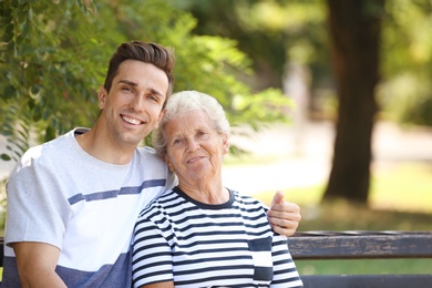 Man with elderly mother on bench in park