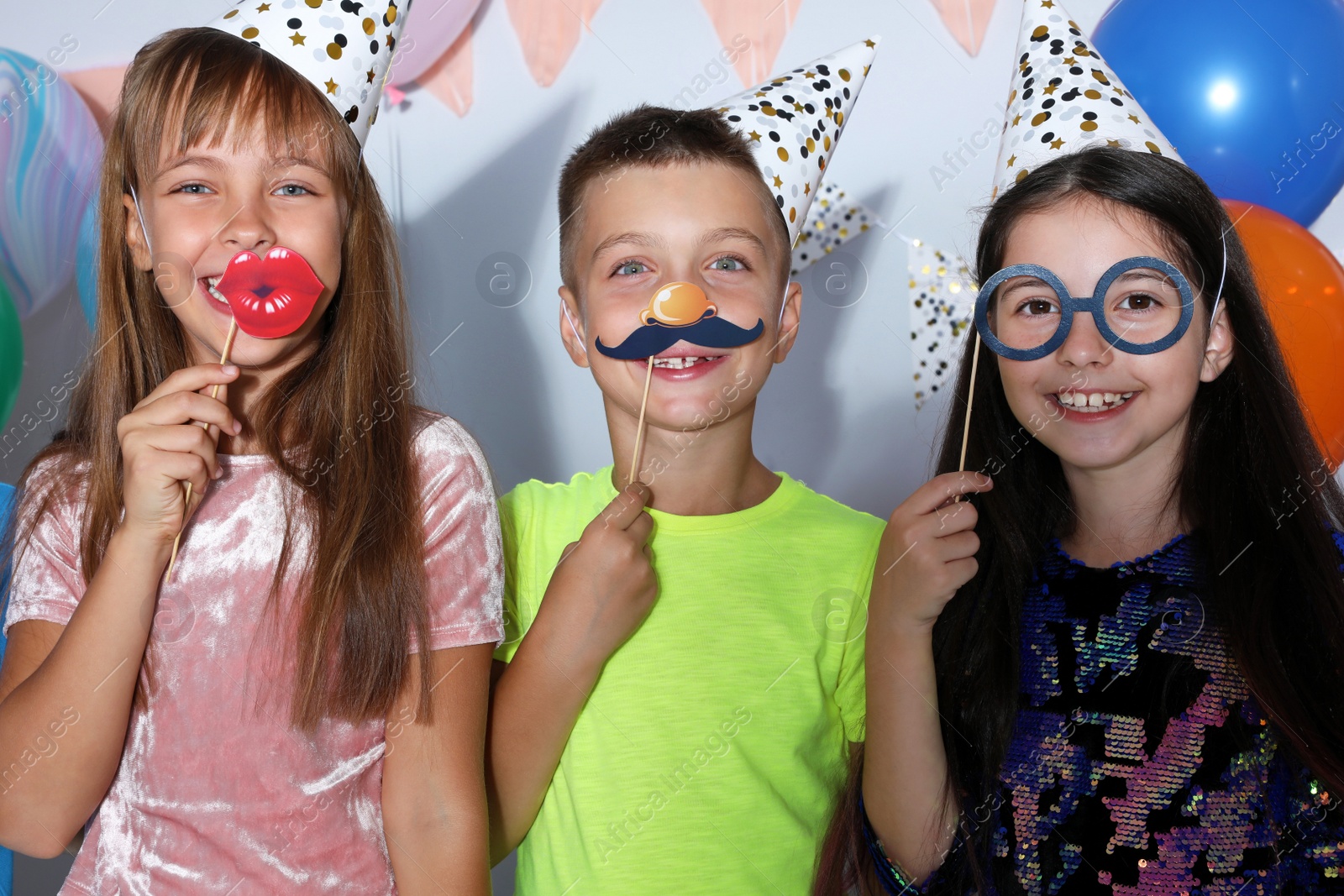 Photo of Happy children with photo booth props at birthday party indoors