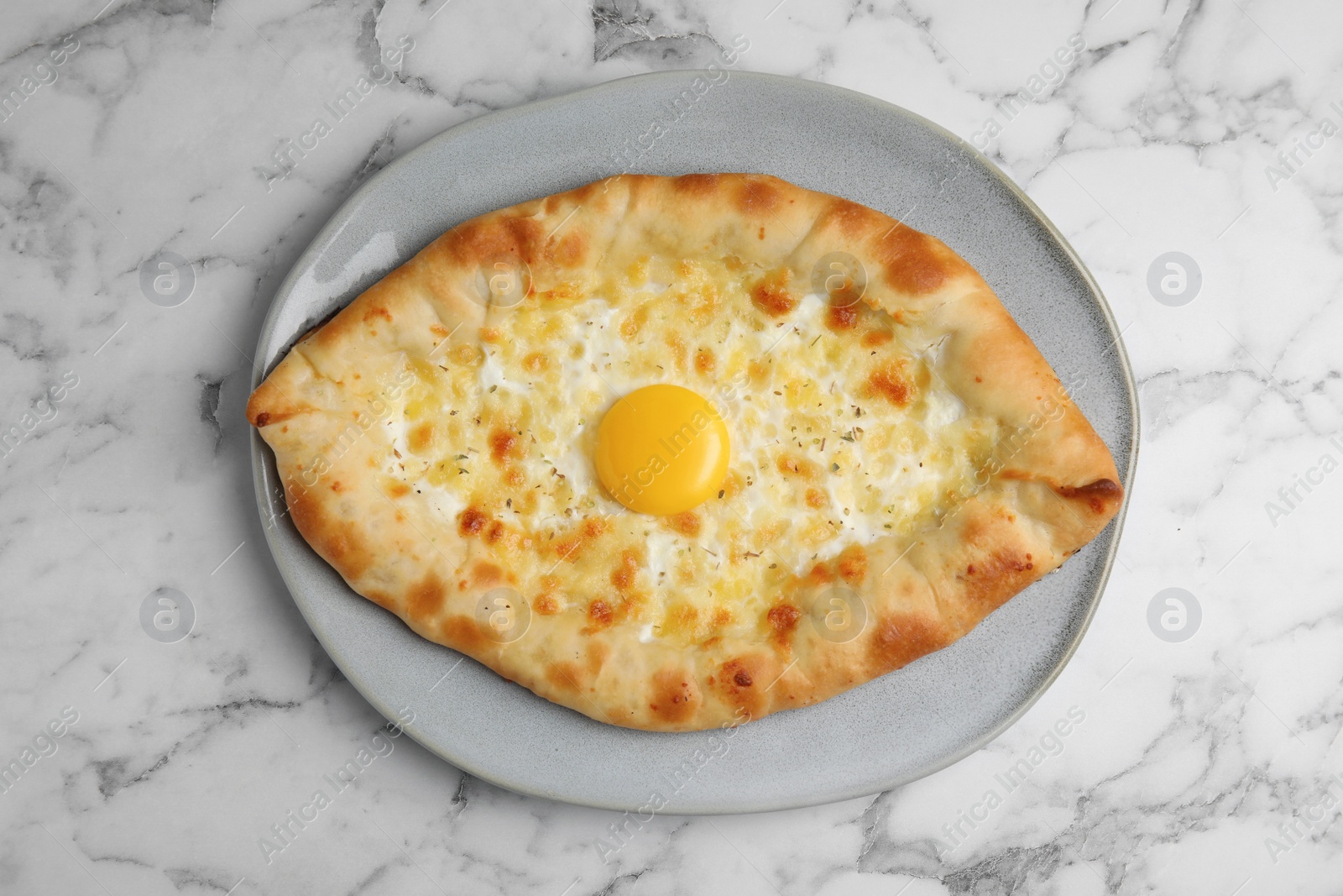 Photo of Fresh homemade khachapuri with cheese and egg on white marble table, top view