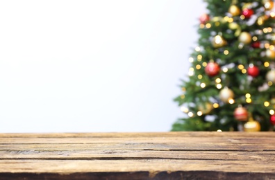 Photo of Wooden table and blurred Christmas tree with fairy lights on background