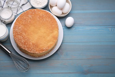 Photo of Plate with delicious sponge cake and ingredients on light blue wooden table, flat lay. Space for text