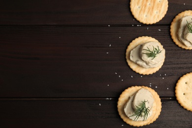 Photo of Delicious crackers with humus and dill on wooden table, flat lay. Space for text