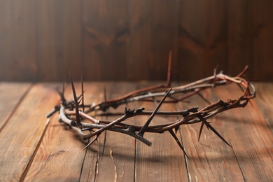 Crown of thorns on wooden table, space for text. Easter attribute