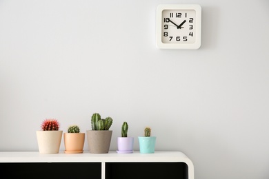 Photo of Beautiful cacti in flowerpots on white cabinet indoors